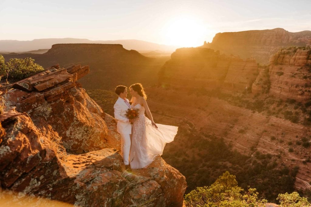 Two brides stand together in the sunset light on their elopement day in Sedona.