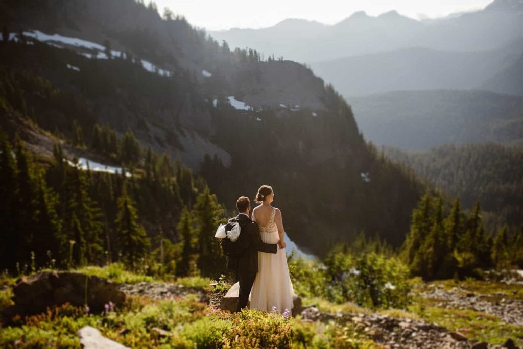 A groom wraps his hand around his bride as they take in the mountain view along the trial together.