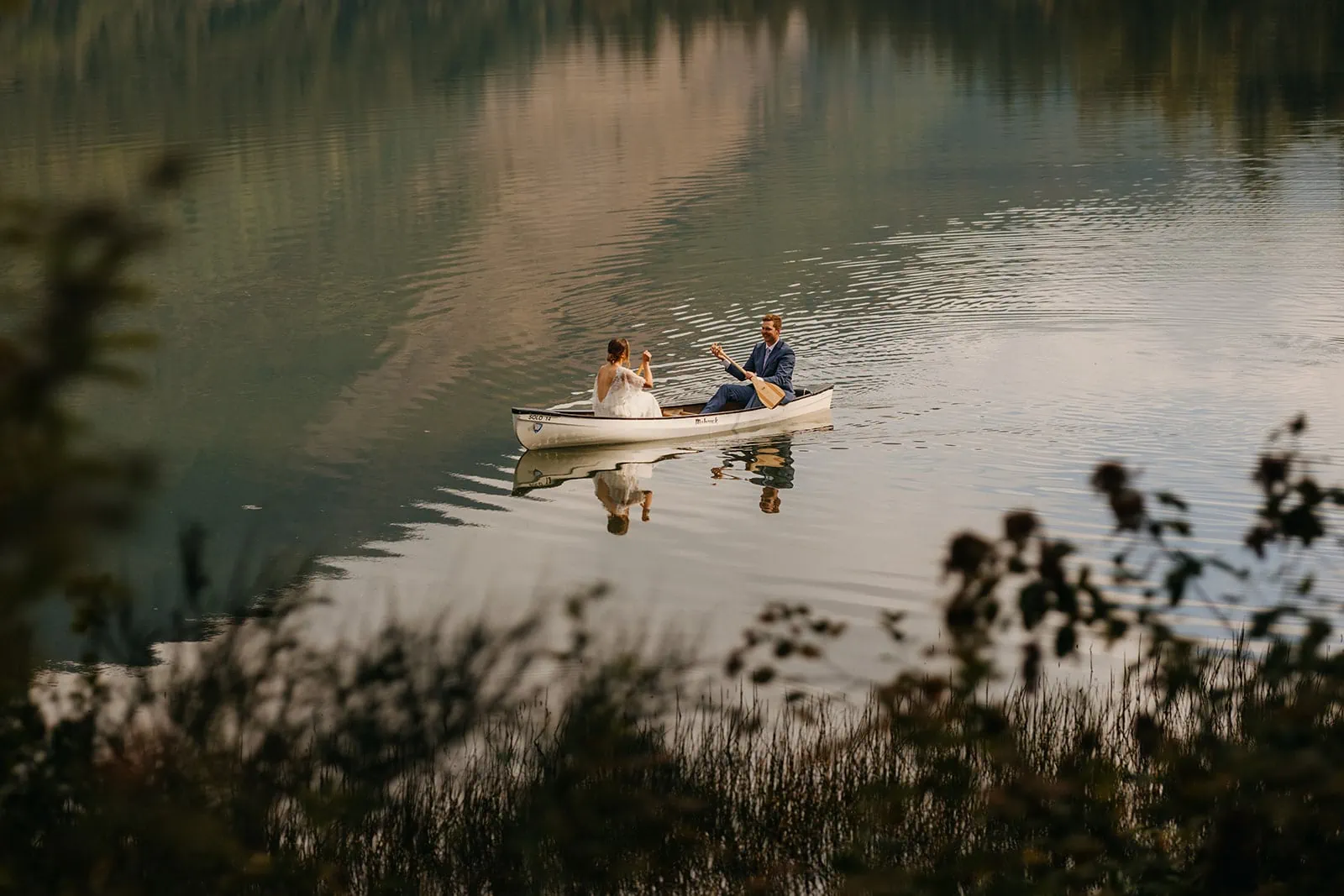 A couple canoes together on a lake on their wedding day. 