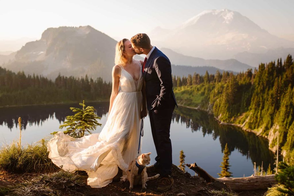 traci and bill kissing in front of mount rainier during their elopement. indy is on a leash.