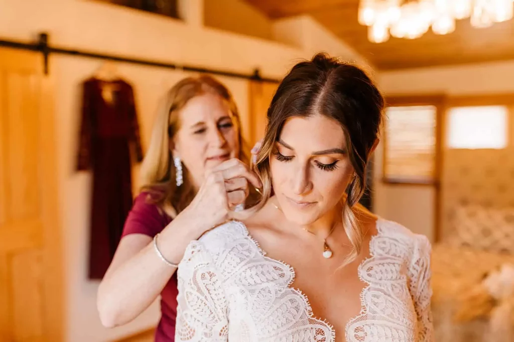 A mother helps the bride by putting a necklace on her