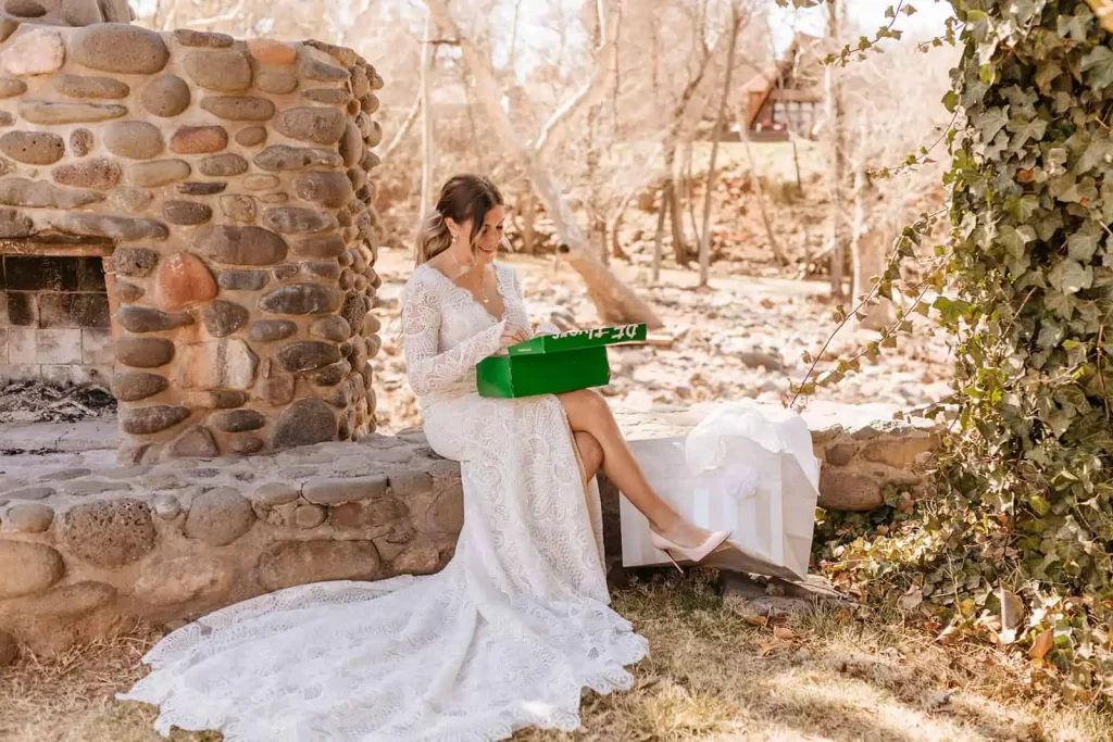 A bride sits as she opens a gift from her groom.