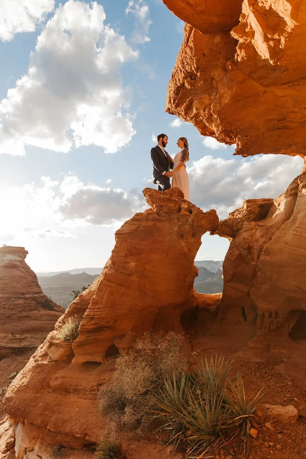 A bride and groom stand together on a rock formation in Sedona.