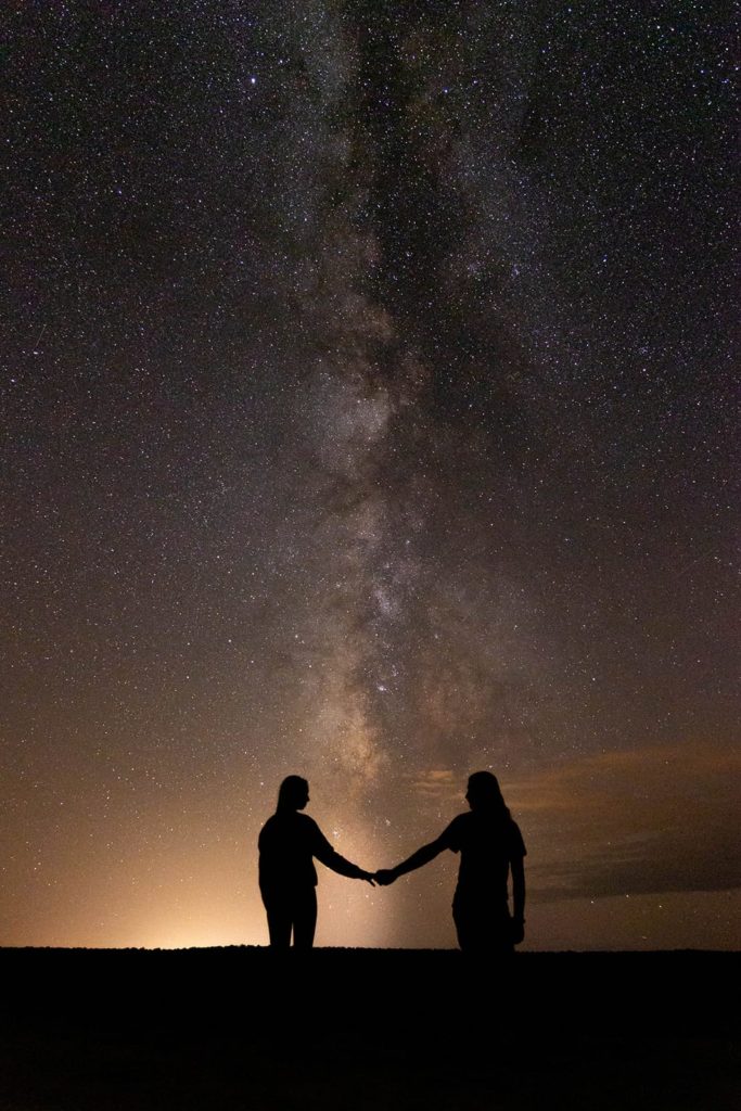 a couple holding hands under the milky way