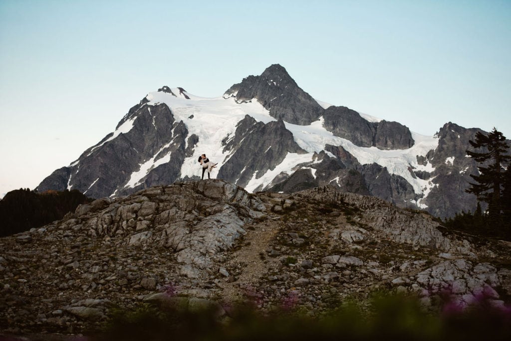 a romantic kiss in the north cascades. the groom is holding the wife bridal style, her arms wrapped around his neck.