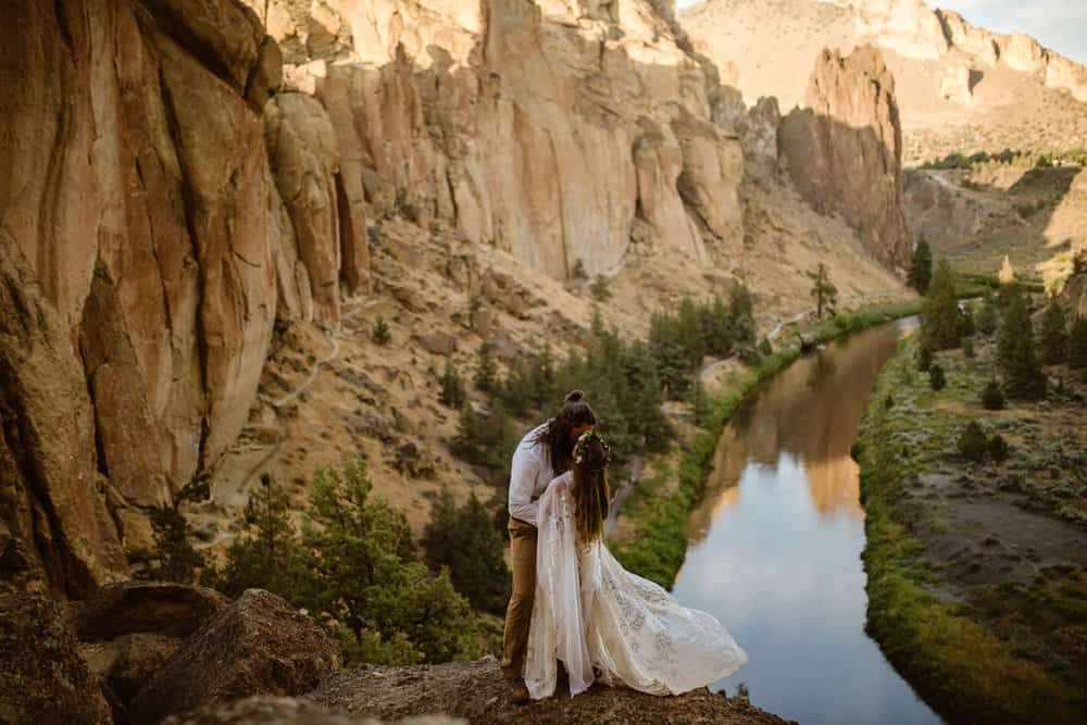 a kiss on smith rock. the rocks and water are in the background.