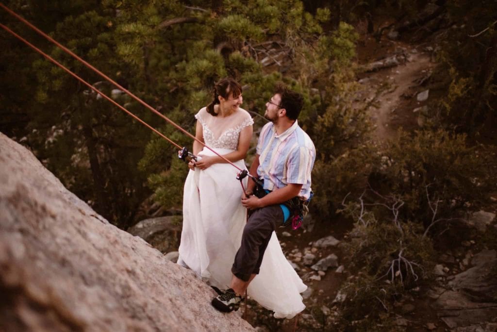 A couple rappels in their wedding attire.