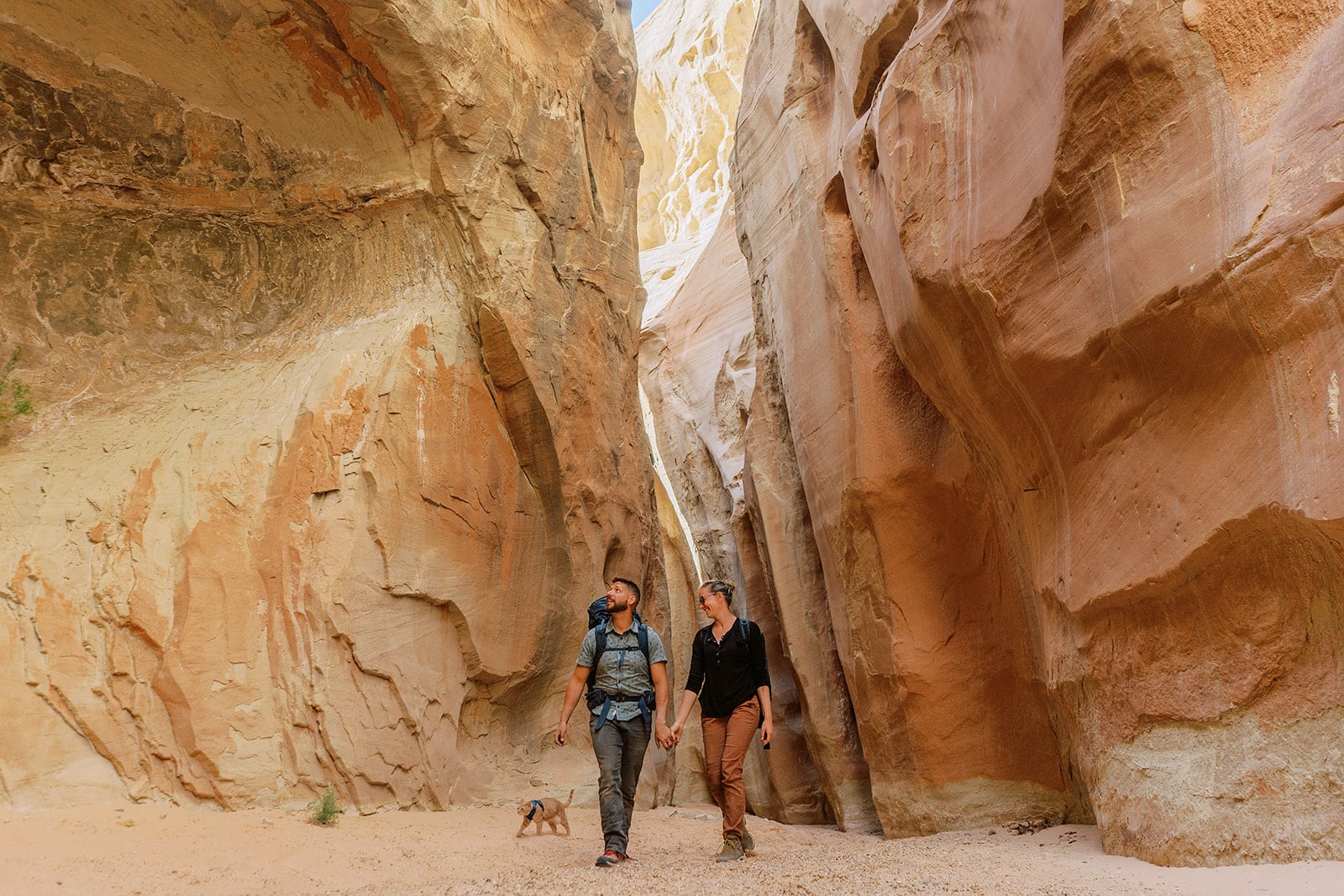 Adventure Elopement Photographers. A couple walks through a slot canyon after repelling in with their cat.