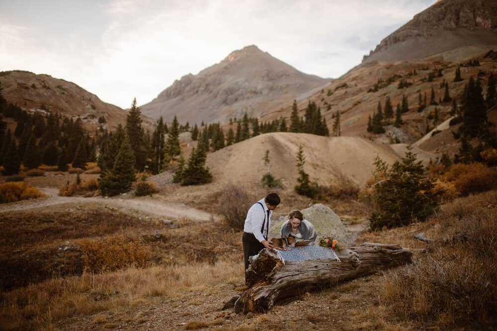 A couple looks together at a map while in the mountains.