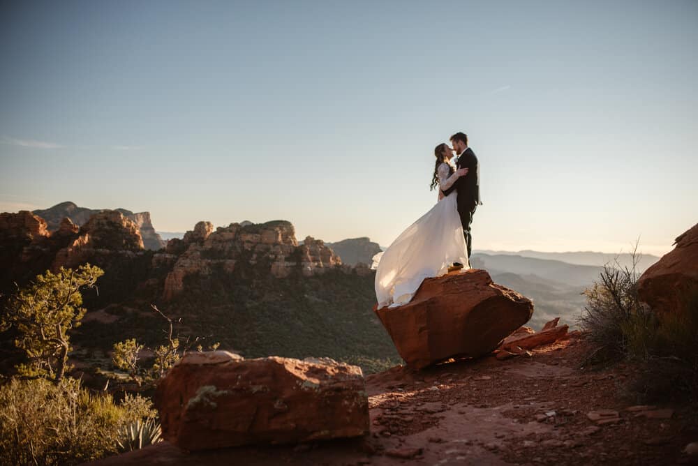 A man and woman stand together at sunset on a vista in Sedona.