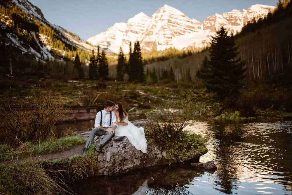 A husband and wife sit together in the mountains of Colorado.