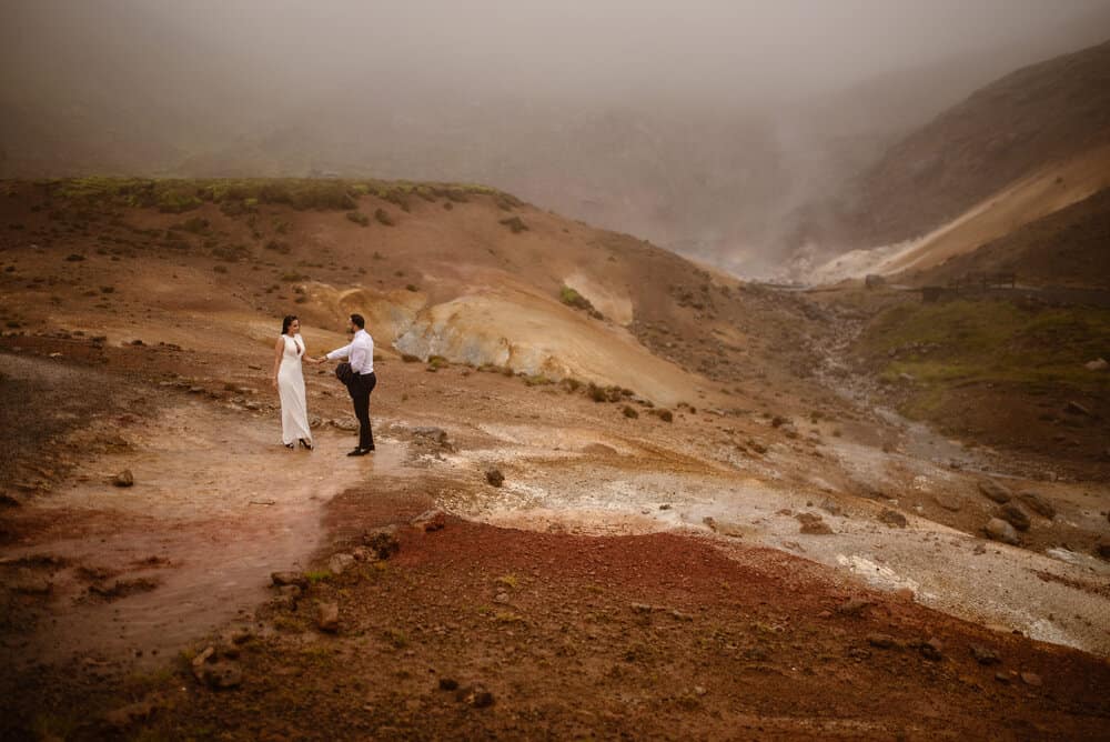 A man and woman hold each others hands on their elopement day as they wonder around the Iceland hot lands. 