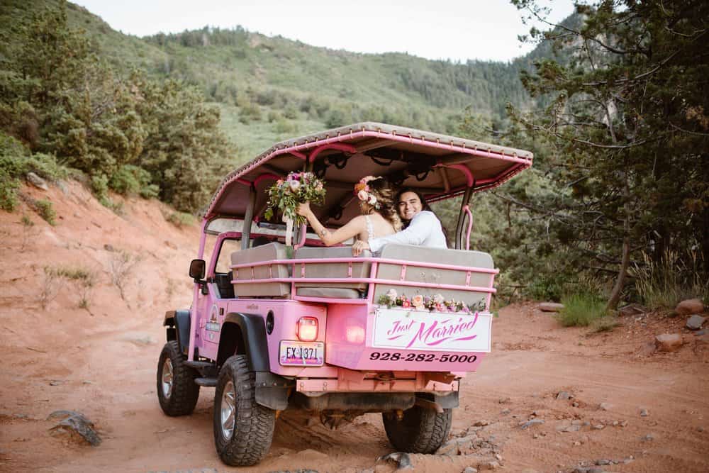 The couple rides away in a pink jeep.