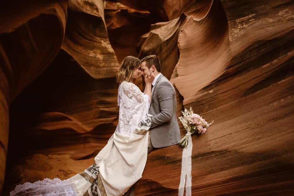 A bride and groom hold each other as they take a break on their slot canyon tour in page, arizona.