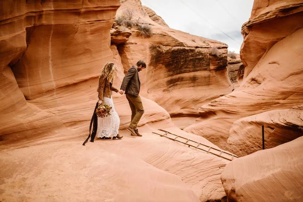 A groom leads a bride into a slot canyon.
