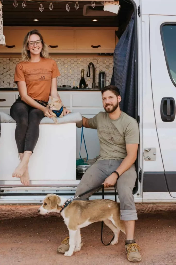 A portrait of a couple, a dog and a cat in front of a van build.