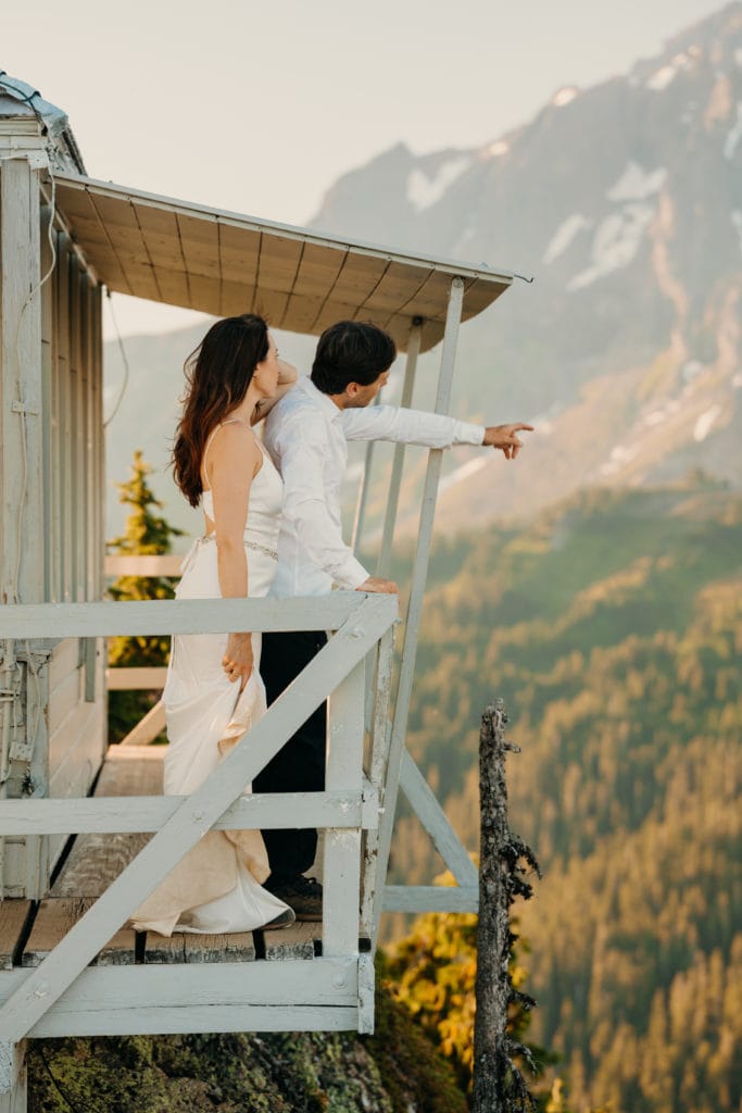 A groom points out the route he usually takes up the mountain from the fire tower with his bride.