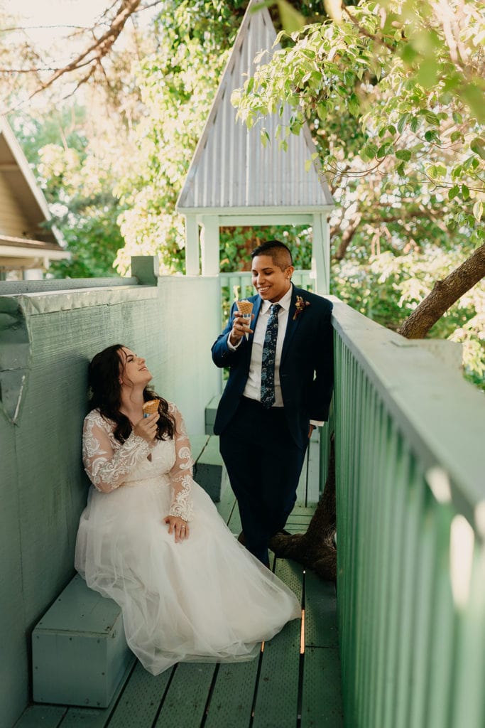 The two brides share their ice cream together in a tree house castle. 