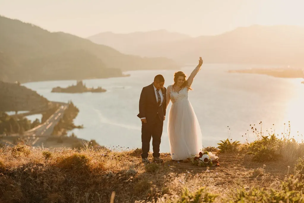 Two brides stand together in celebration of their elopement ceremony at sunset.