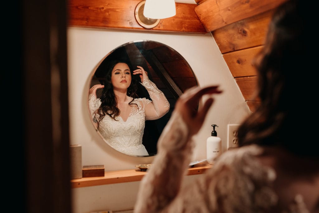 The bride looks in the mirror after putting her dress on for final touches. 