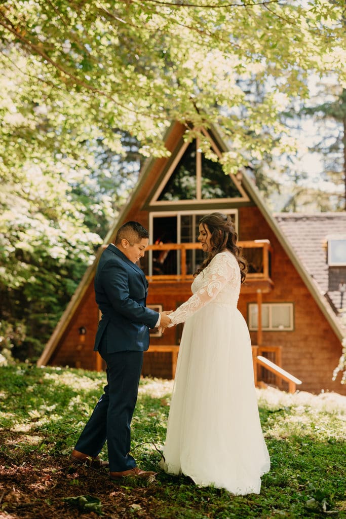 The brides share their first look in front of the A frame cabin. 