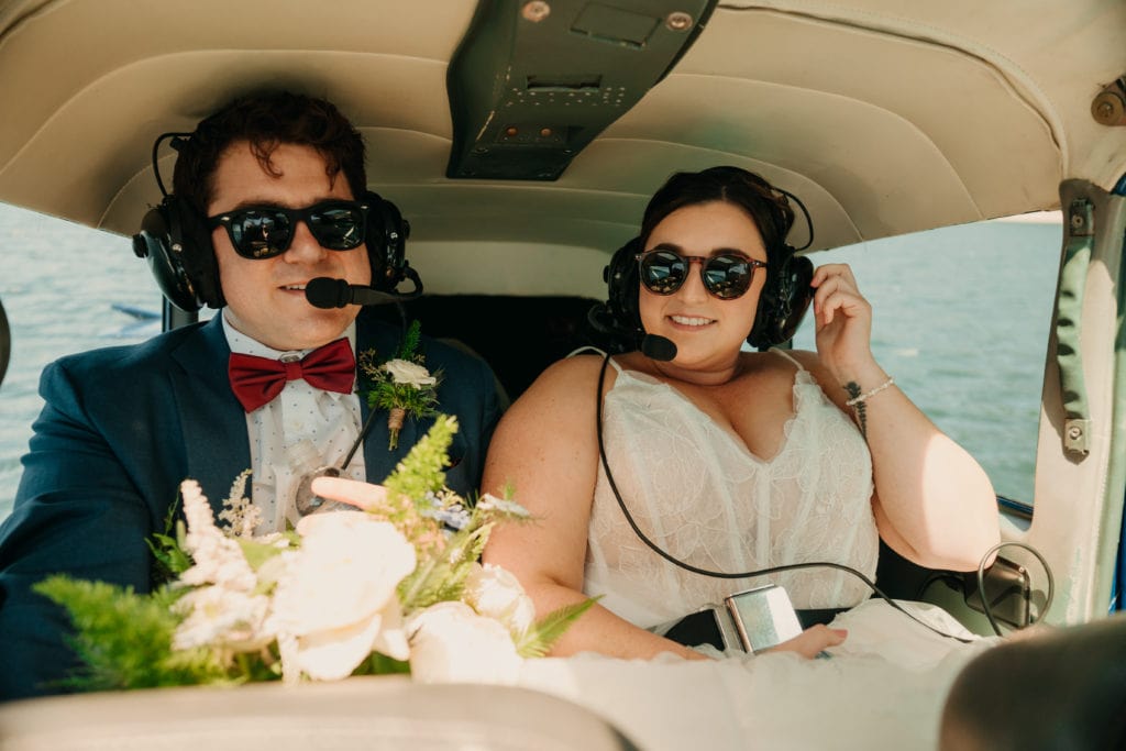 A bride and groom sit together on a sea plane