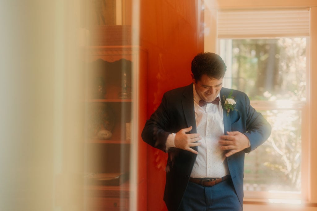 A groom putting on his jacket