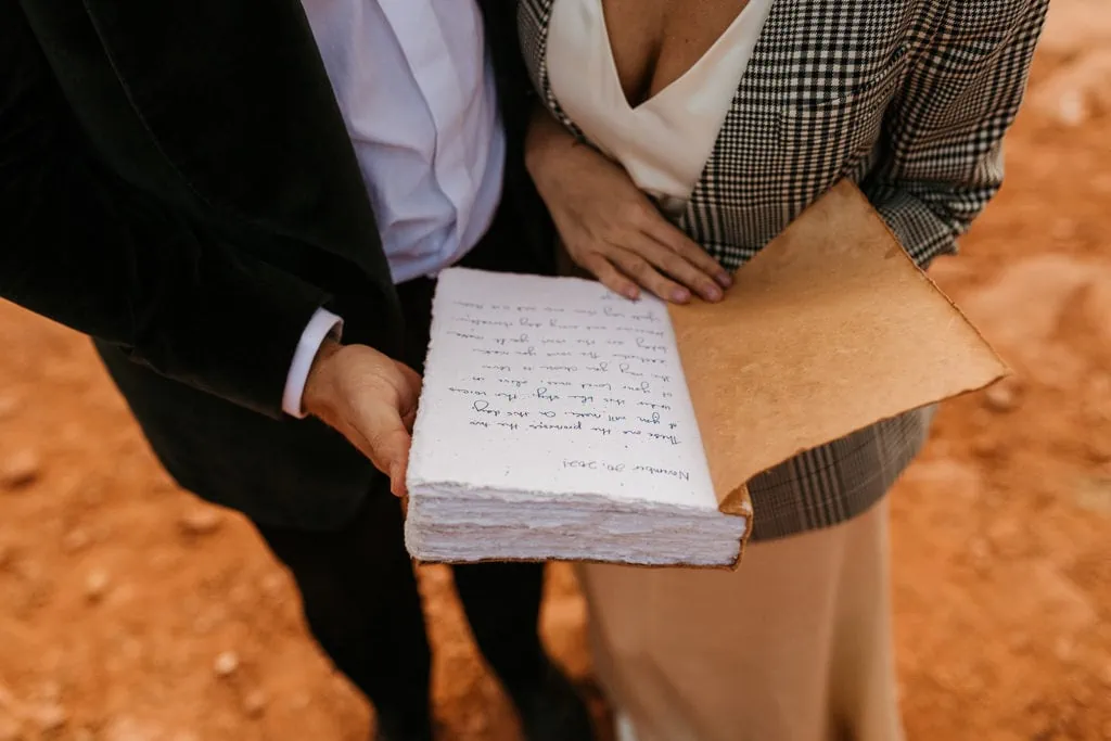 A couple holds a book containing marriage advice from all of their loved ones which became their vows. 