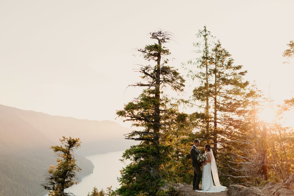 A couple shares their private vows at sunset on the trail overlooking lake crescent in Olympic National Park. 