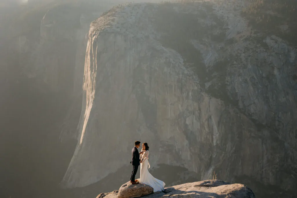 A couple stand small in the big landscape as they share private vows together. 