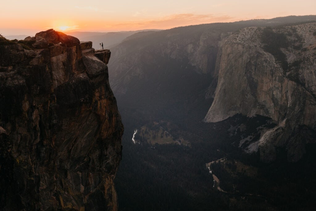 A view of a couple standing at Taft Point at sunset for their wedding. 