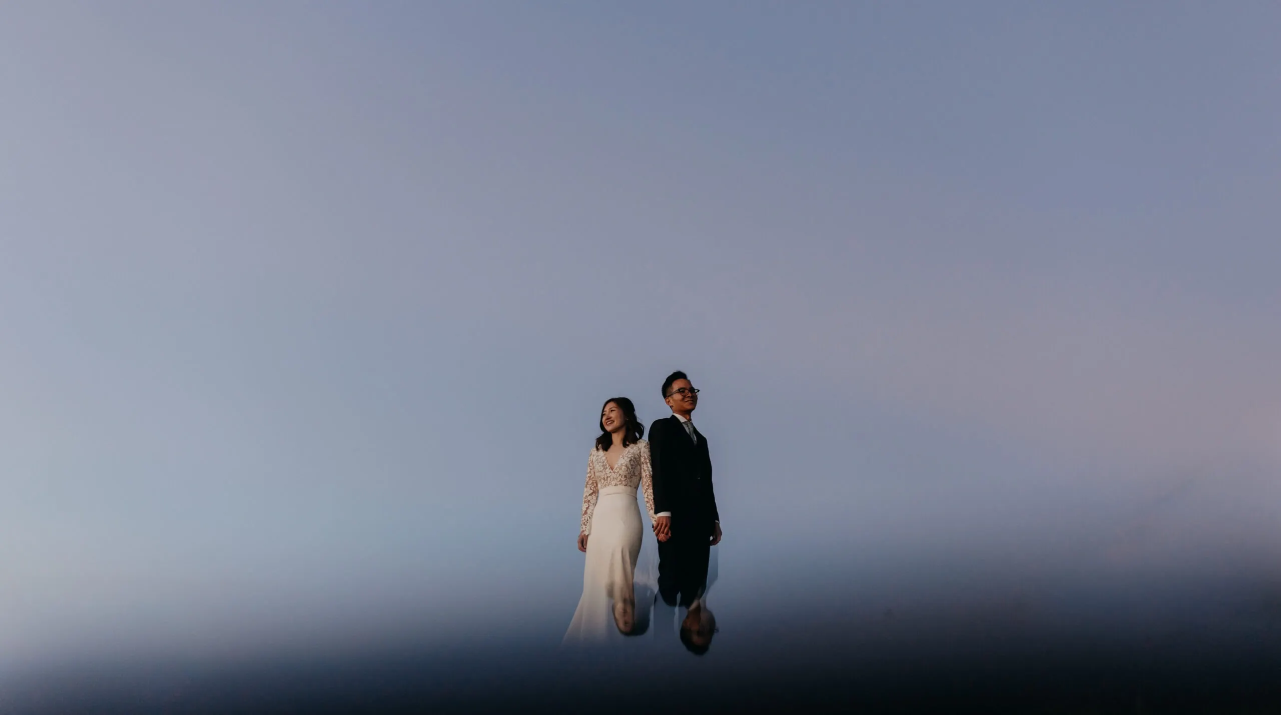 A bride and groom smile during blue hour. 