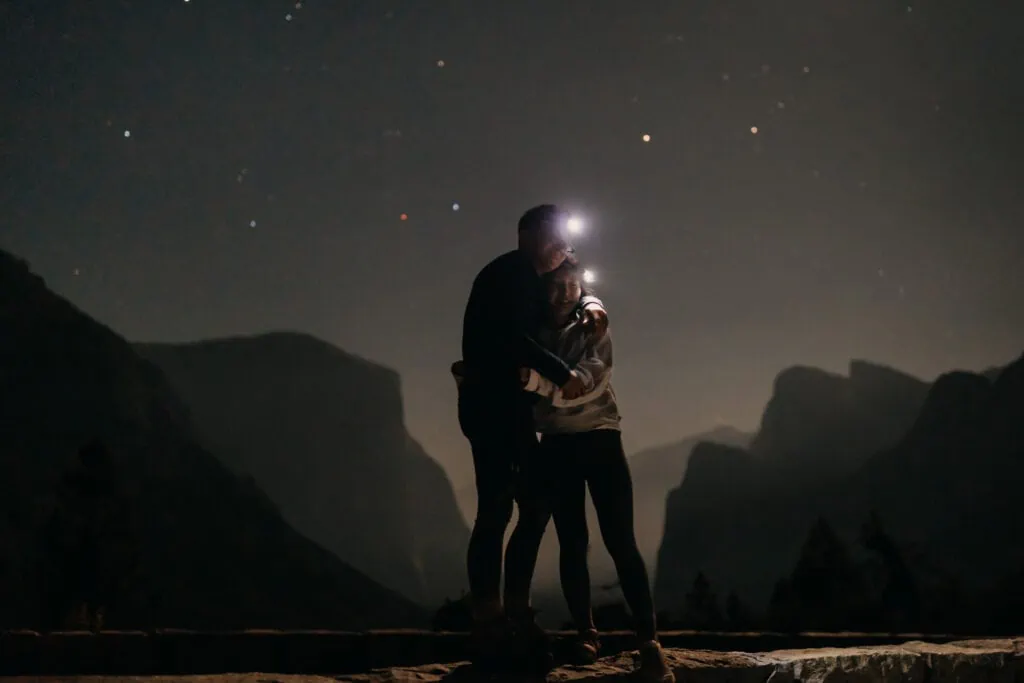 An image of a couple hugging at the end of their hike in Yosemite at 1am. 