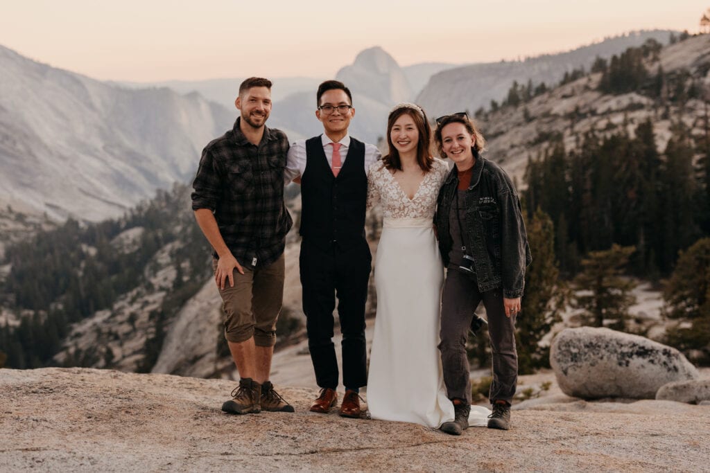 Two wedding photographers take a portrait with their couple.