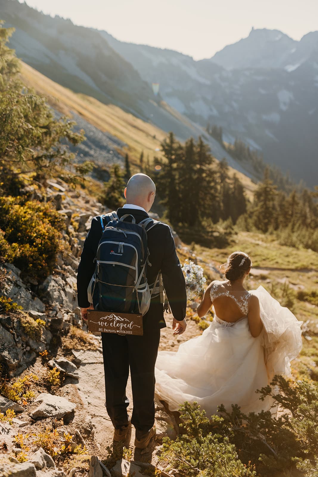 A couple just married hike down the mountain together.