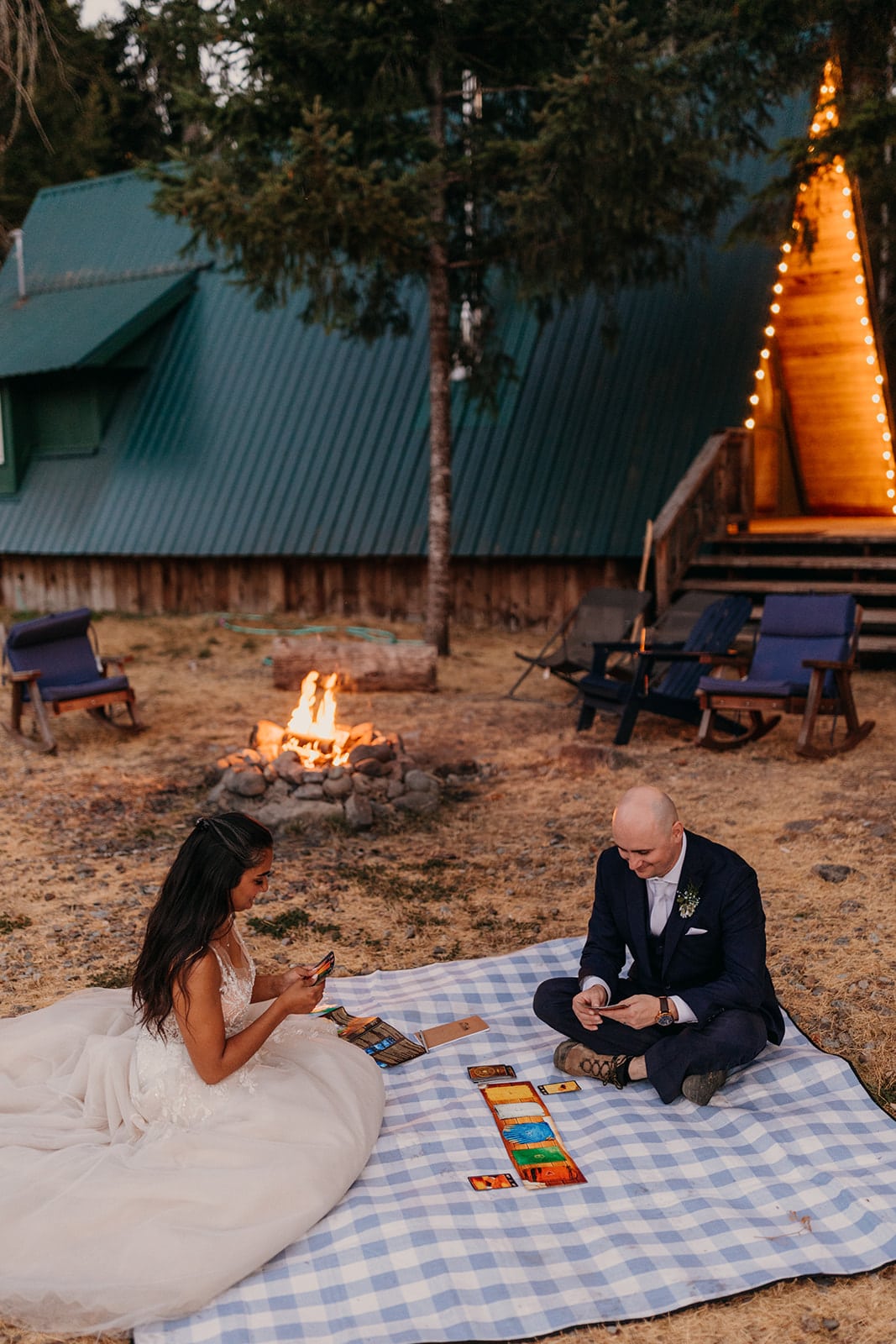 The bride and groom play games together by the fire. 