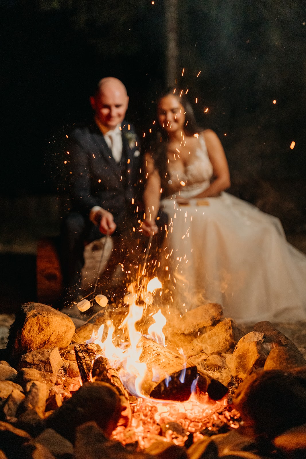 The couple roasts marshmallows by fire. 