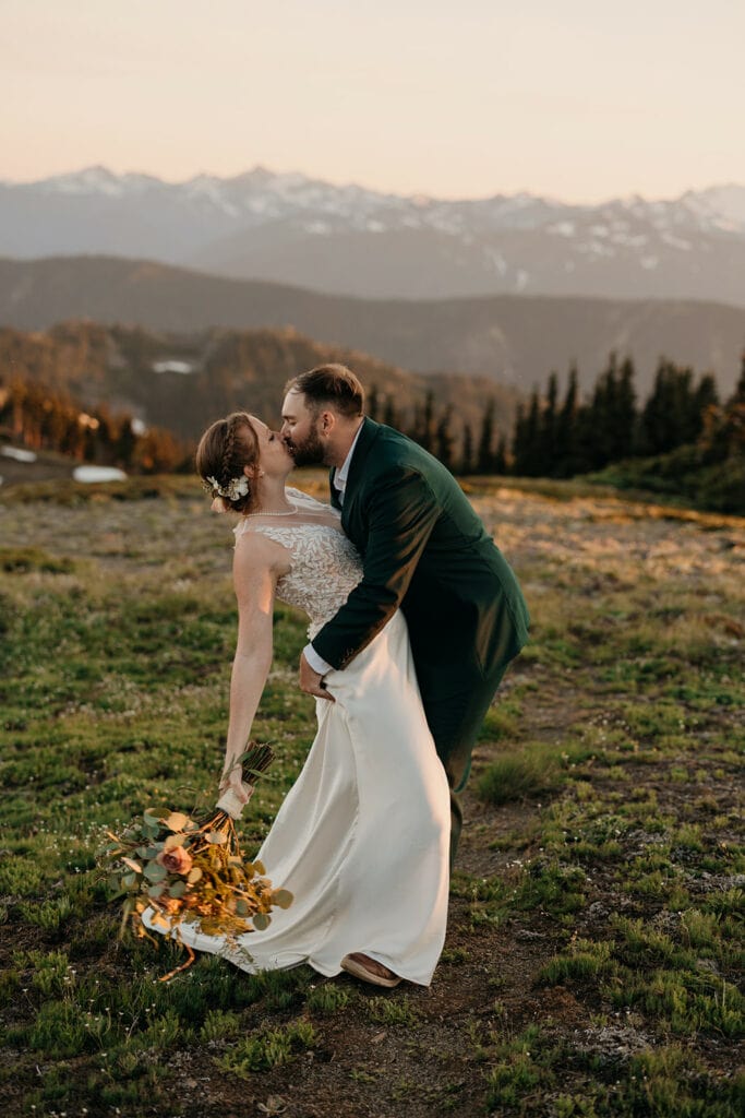 A groom kisses his bride on the trail at sunset in the mountains in Olympic National Park. 
