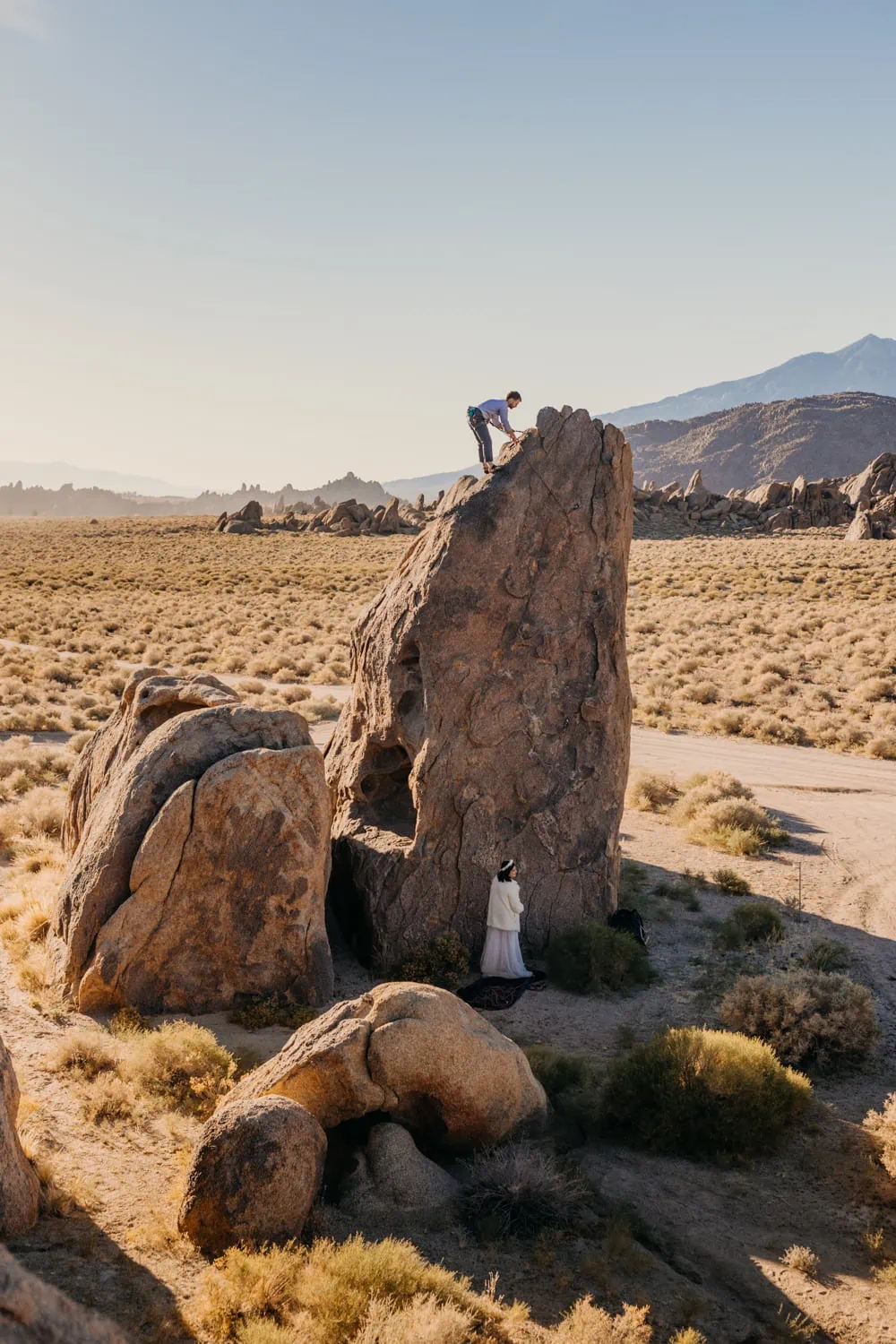 A groom tops out on a climb on a sunny day in Alabama Hills.