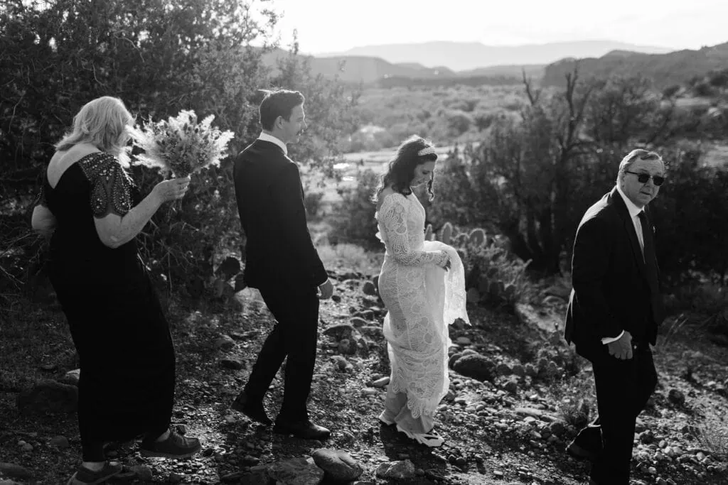 a black and white image of the bride and groom walking to their ceremony.