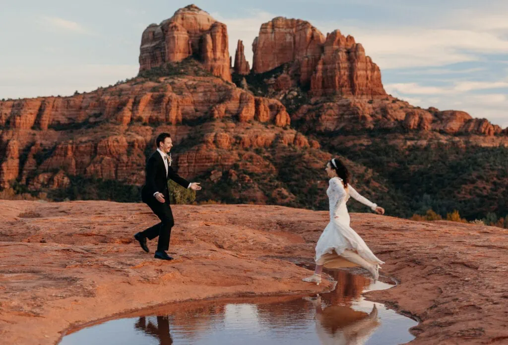 The bride and groom run towards each other with Cathedral rock in the background.