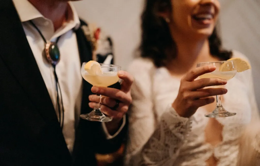 A detail photograph of the bride and groom holding margaritas.