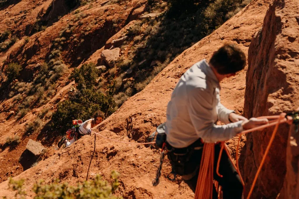 A groom belays his bride up to the top of this sedona rock climbing route.