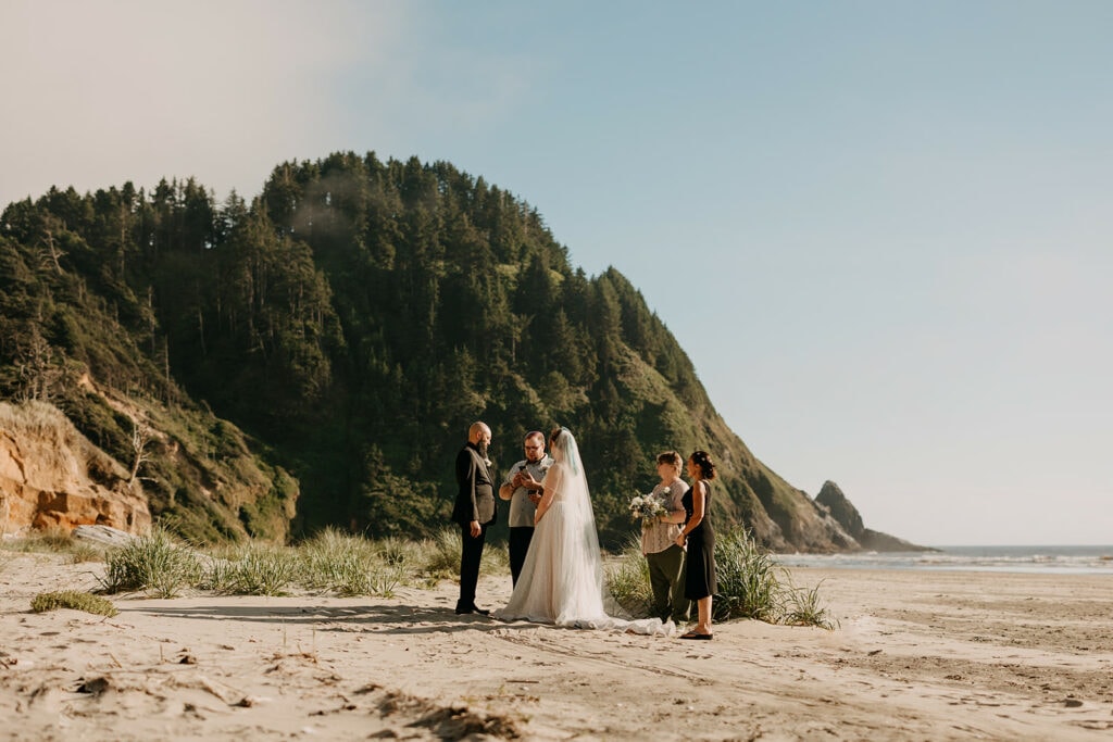 A couple listens to their officiant during their elopement ceremony on the Oregon coast. 