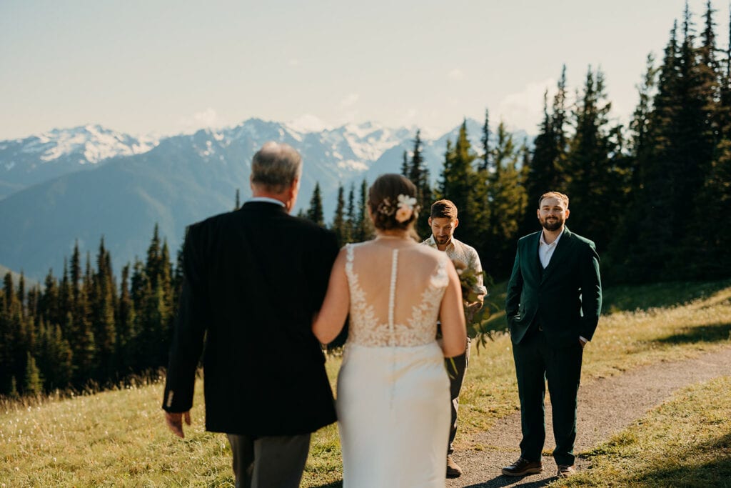 A father walks his bride down the trail to her elopement ceremony.