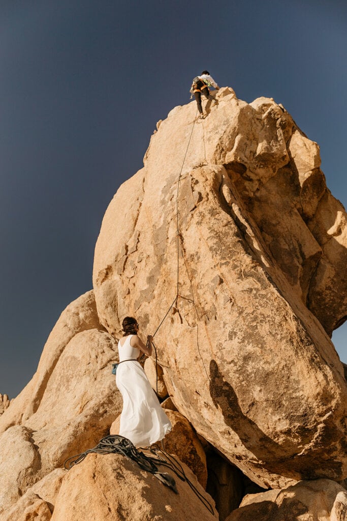 A bride and groom climbing in Joshua tree on their wedding day. 