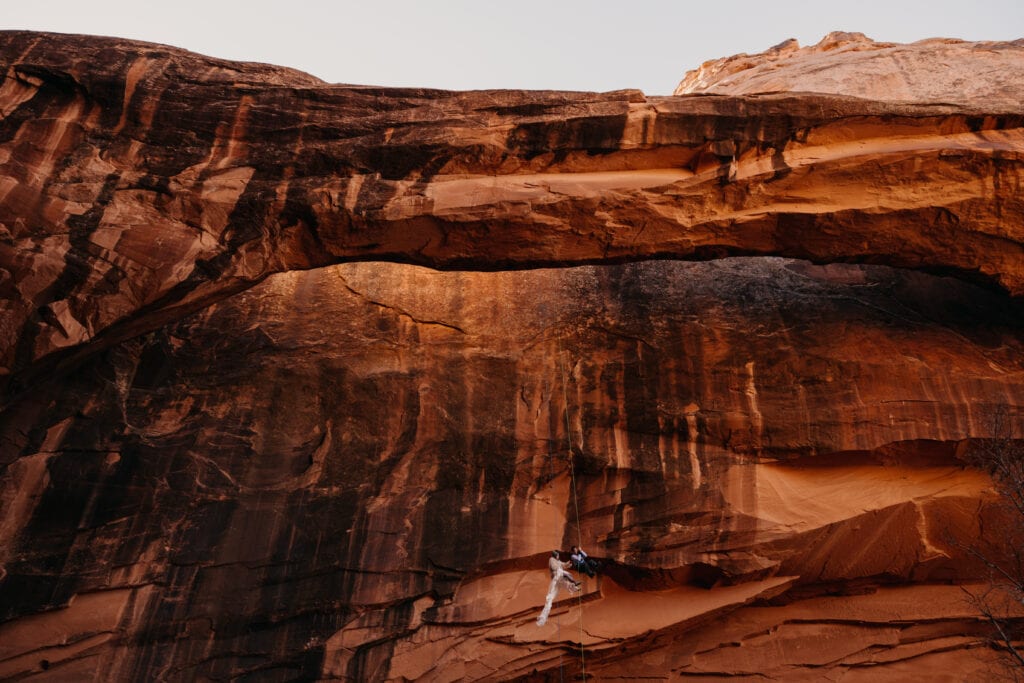 A couple raps down a canyon on a winter day in the morning for their adventure elopement.