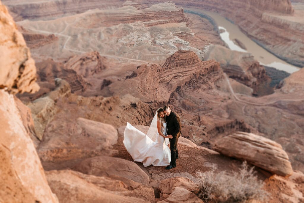 The bride and groom share a kiss overlooking a dramatic canyon in Moab.