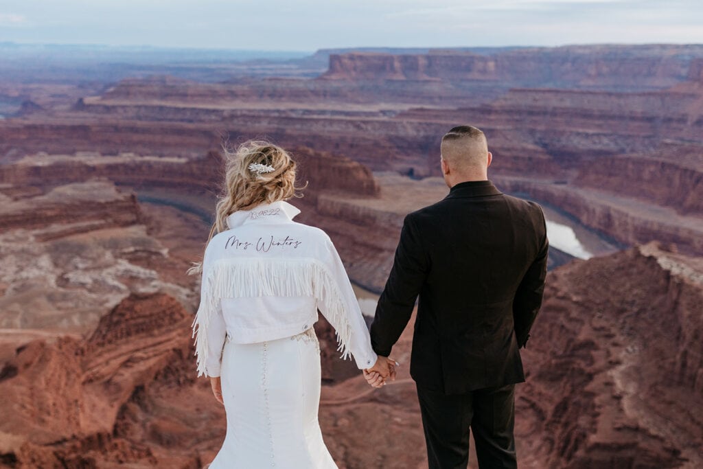 The bride and groom look out over the canyon as the last light is filling the space.