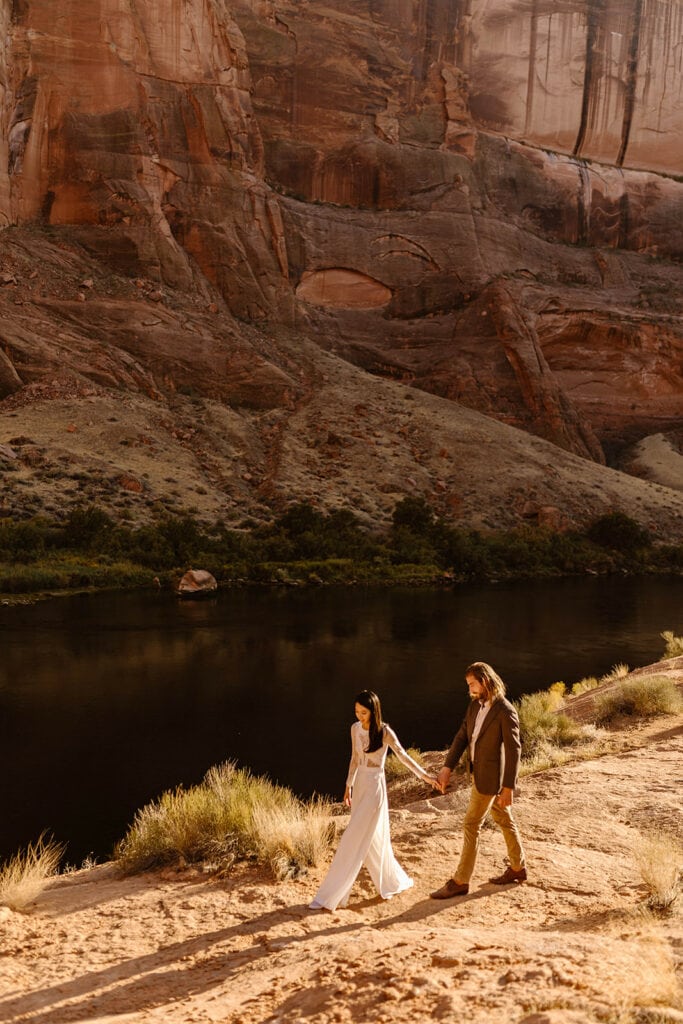 A couple walks along the rocks by the Colorado river.